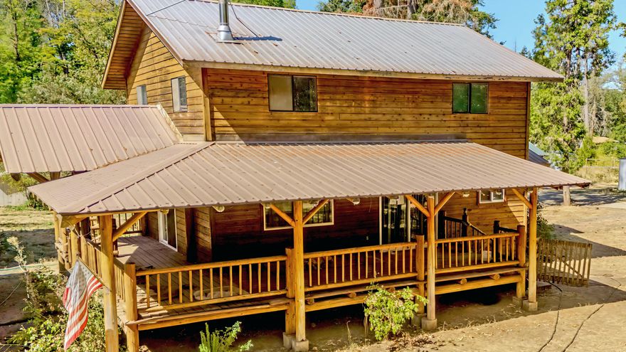 This is the creekfront hobby farm you've been waiting for!  Step inside this 2-story Pacific Northwest cabin-style 1,548 sq. ft home with 3 bedrooms and 2 bathrooms on 5 flat acres. Inside, rich tongue-and-groove wood walls and ceilings exude rustic charm, blending seamlessly with modern comforts. Unwind on the handcrafted log spindle deck, soaking in the peaceful country setting.  Embrace serenity by your private pond and scenic Elder Creek frontage, perfect for quiet evenings. Bring the RV! This property is road-tripper approved with RV hookups.  Expansive pastures and thriving apple trees invite gardening or livestock ventures, while a 2-story barn, durable sheet metal-sided workshop, and multiple outbuildings offer ample storage for hobbies or projects.  This property embodies the essence of a nature-inspired lifestyle. Don't miss the chance to own this treasure—schedule your private tour today!