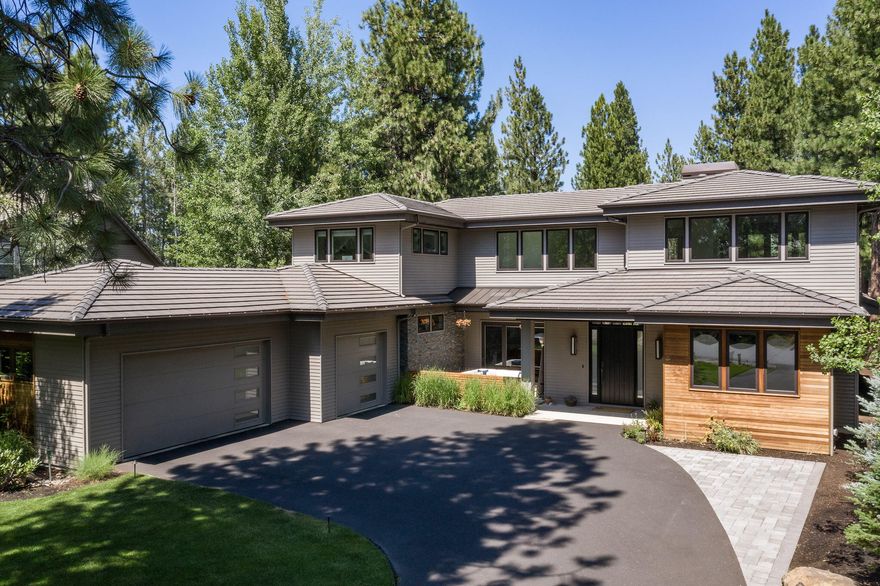 This modern contemporary Broken Top home begins at the welcoming front patio, leading the way into the bright and airy interiors benefitting from an expansive accordion glass wall in the great room that opens to spacious outdoor living area, complete with bbq kitchen/dining/lounging spaces, hot-tub patio, & lower patio firepit seating overlooking the cascading waterfall and pond. Back inside, the bright and cheerful kitchen will inspire the gourmet chef in the family with top-of-the-line appliances, enormous walk-in pantry with a kegerator & beverage fridge. The main level primary suite overlooks lovely garden & waterfall views and encompasses a truly luxurious bath. Main level also features a second full en-suite bedroom, as well as two separate offices. Upstairs is home to two addtnl spacious guest rooms and comfortable family room, the perfect retreat for family and guests. Stunning home spans 4,221 sq.ft. on a nearly ½ acre private oasis, set within the gated Broken Top community.
