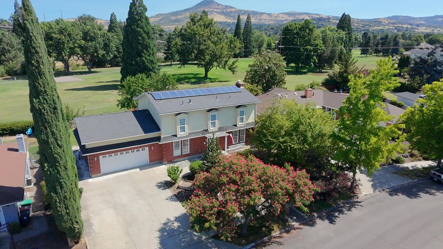 This East Medford Colonial style home with many updates sits on the 5th Fairway of the Rogue Valley Country Golf Course. The kitchen is a chef's dream with a double oven, granite island, farm sink, and upgraded cupboards with pull out drawers. The dining room is adjacent to the kitchen and opens to golf course views with French doors. A half bath, large living room with fireplace, and office are also downstairs. Upstairs features the large primary bedroom with deck overlooking the golf course and three guest bedrooms. The front landscaping is park like with a monkey puzzle & mimosa tree while the large back yard has garden beds.