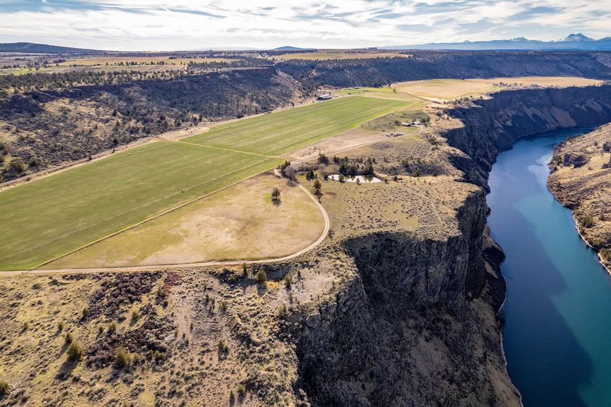 The Crooked River Rim Farm is a package for the land investor looking for majestic settings with agricultural production. Watch black tail bucks wade through lush hay fields as you tend to your gravity fed irrigated farmland, that grow a multitude of crops. End the day with enjoying sunsets fading away over the Crooked River Canyon Rim. Build your dream home on the rim to enjoy privacy and scenic vistas that are rare. The Crooked River Rim Farm consists of 456.83± acres with 183.9± acres of NUID water rights and borders the Crooked River. The property sits high above the river, on a bench in the canyon, and elevates again to a view of the Cascade Mountains, including Mount Hood. There is 1956 stick built home, currently used by ranch manager, and 2 mobile homes used as place holders for future dwellings. Irrigation improvements consists of 2 half pivots, 6 wheel-lines and set hand-lines. Other improvements include a large 800± ton hay barn, heated shop and two sheds.