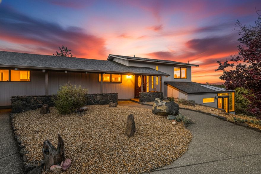 Enjoy main-level living at its best with panoramic views stretching from the Cascade Mountains to Smith Rock. Nestled on 2.74 acres, this home offers an open living area with a rock-surround fireplace and double sliding glass doors leading to a spacious deck overlooking the water feature and stunning mountain vistas. The main floor includes an open kitchen, dining area, second living space, office, and laundry room. Downstairs, a daylight basement provides a versatile studio-style suite with a full bath and bar area, perfect for guests or use as an ADU. Experience the tranquility, space, and breathtaking scenery that make this property truly exceptional.