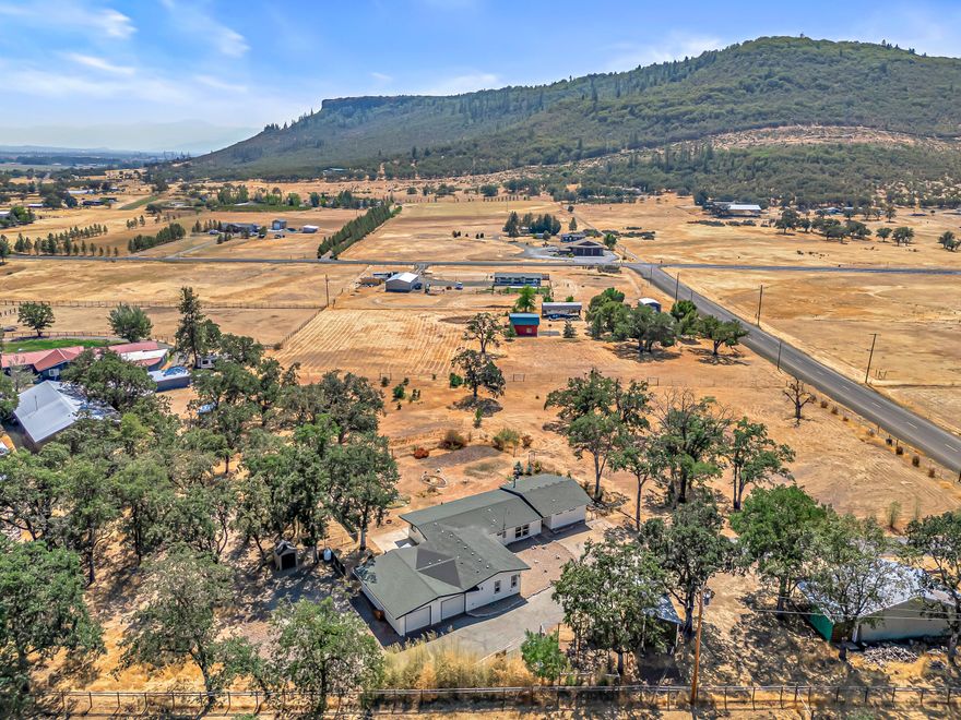 This stunning home sits on a level 3.06-acre property with breathtaking views of the Table Rocks and surrounding mountains. Completely remodeled in 2022, every detail has been refreshed—new kitchen with custom cabinets, granite counters, and propane range, a gorgeous primary suite with a walk-in tile shower, and a custom closet. The home features 3 bedrooms, 2.5 baths, plus an office with built-ins, laminate flooring and mini-splits throughout, and a wood stove. The attached 630 sq ft ADU also offers its own entrance, bedroom, bath, kitchenette, and living space—perfect for guests or multi-gen living. Updates include all new electrical, plumbing, plus a brand-new well pump and tank (2024). Additional property highlights: oversized 2-car garage with workbench, 24x40' shop, RV parking, dual wells, chicken coop, lamb shelter, fenced and gated grounds. Room to garden, homestead, or simply relax—this home feels and lives like new!