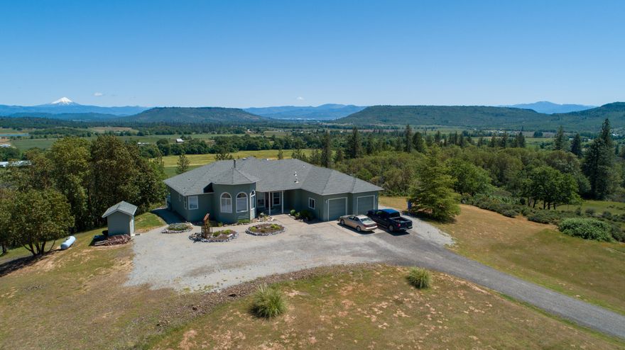 Panoramic views from this amazing country retreat!  This custom home is situated on 17.4 acres with lots of space for wildlife, like elk, to roam!  This 2,156 sq ft single story home features an open floor plan with vaulted great room w/wood stove, plant shelves and patio doors. The kitchen has an island, propane range, granite counters, a pantry and a broom closet. This home has a split floor plan with 2 bedrooms, 1 bath on one side & on the other side a 3rd bedroom/office and the master bedroom.  The master suite has tray ceilings, his and hers closets, patio doors to covered deck, double vanities, walk in tiled shower, and jetted tub. Out back you will find a composite deck, propane hook ups for BBQ, planters with drip/sprinklers and a fenced yard – a peaceful setting to enjoy the quiet, the views and wildlife!  This 1 owner home was custom built in 2000 by Ray Williams w/ 360 degree views of Mt. McLoughlin, Mt. Ashland, upper and lower Table Rocks & city night lights.