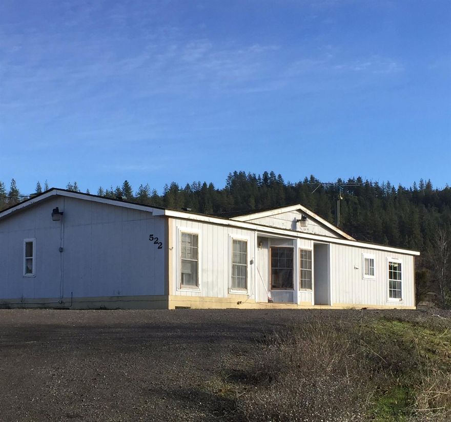 Lot's of potential in this one! Five level to gently sloping acres with surrounding mt. views and a seasonal creek. 3 bedrooms, 2 bath manufactured home with a split floor plan, vaulted ceilings & laminate flooring. Large master with soaking tub, separate shower, walk-in closet. Outbuilding/potential barn, newer well pump, newer septic pump, good well per owner. Home needs work but with some elbow grease it could shine! Or remove the manufactured home for a new home.