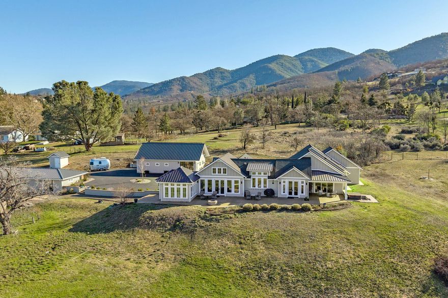 This stunning, gated, single level custom home completed in 2019 is set on 6+ acres, has breathtaking 180-degree views, is conveniently close to Ashland's downtown yet private. The light and bright craftsman-style 3,165 sq ft home blends elegance and function with vaulted ceilings, multiple fireplaces, large chef's kitchen and primary suite. The additional wine cellar, sunroom, office, guest en-suite bedroom, wheelchair accessibility plus courtyard, extended patio with a gas fire pit, and separate terrace with a natural stone wood-burning fireplace maximizes indoor/outdoor living. A charming, detached 935 sq ft, 1 bedroom, 1 bathroom guest quarters, oversized 3-car garage with workshop/art studio/fitness room, shed, large solar array, high-producing well, 2 x 2500-gal rainwater catchment tanks for irrigation, geothermal heating and back-up natural gas generator round out the property. This is a must-see for anyone seeking luxury, comfort, and convenience. Features Sheet attached.