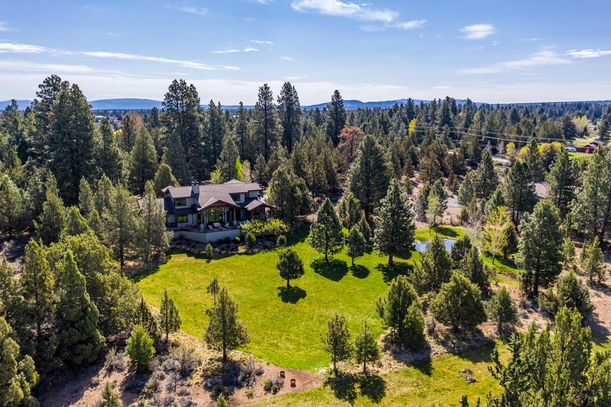 Just minutes East of Bend, this tranquil 23-acre retreat rest among beautiful pine trees. Two acres of irrigation feed the pond, connected to underground sprinklers creating easy care park like setting. Enter through the stacked stone courtyard to the 4000+ SF custom built home with rich hickory wood floors, New Zealand wool carpet, natural stone fireplace & knotty alder solid doors + a gorgeous wine cellar. Kitchen features granite slab counters, high-end appliances, custom cabinets & large island. French doors open to the spacious deck with elevated terrain & Cascade Mt. views + sunken hot tub. Main level master offers sliding door to deck, 2 walk-in closets, spa tub & walk-in tile shower. Upstairs features en-suite guest room + additional bedroom, den & 3rd full bath. 3 car garage & large shop area also attached to the house. Impressive custom car barn features 8 double doors(2 for RV access), kitchenette, half bath, heat/AC & large upstairs storage room. Truly a special estate.