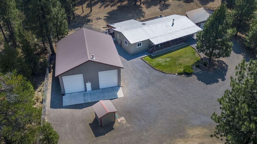 Looking for spacious shop, detached garage, 1782 sq ft of living space, 2 covered decks and a greenhouse?This property has all of that and more! Situated nicely on a 1-acre lot, this 3-bed, 2-bath home offers a peaceful & private setting. The entire property is fully fenced with 2 front gates, providing peace of mind & security. Shop is 36x40. Both bays are 14 ft tall, 12 ft wide. Located less than 5 miles from town, it is minutes from pickleball, ball fields, playground, dining, grocery shopping & schools! 
Enhanced safety during wildfire season due to major tree and brush removal. Very large living room allows for a home gym, home office or play area. Large dining area could be walled in to create a den. Primary suite is separate from the guest bedrooms. Both bathrooms have been remodeled.Updates include fresh protective roof paint, new lighting, carpet, baseboards, barn style pantry door, water softener and extended covered walkway to garage.Floorplan attached. FHA,VA,Conventional