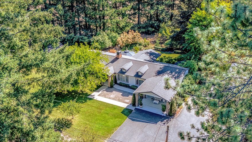 Discover this exquisite 3-bed, 2 1/2-bath home on a 1.87-acre lot, blending luxury and function! Inside, enjoy travertine tile flooring, a cozy woodstove with travertine hearth, and crown molding throughout. The kitchen dazzles with a skylight, while the primary ensuite features a dual-sink vanity and tiled shower. Relax on the patio, the trex decking deck, or hot tub. Outside, a vibrant garden with roses, lilacs, fruit trees, and a koi pond creates an oasis. A heated greenhouse and 16x16 studio building offer creative spaces. The oversized 2-car garage, housing 3 cars, a riding mower, includes 16 upper and 8 lower storage cabinets, 7 ft and 12 ft workbenches, two 6x8x2 fixed cabinets, and a 2x2 bench with storage, ensuring ample workspace. A metal carport could be used as RV storage, and a 9,000-watt generator provides backup power. With a 2-year-old roof and spacious office, this meticulously maintained retreat is perfect for work or creativity. Schedule your tour today!