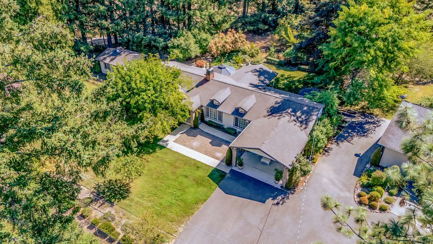Discover this exquisite 3-bed, 2 1/2-bath home on a 1.87-acre lot, blending luxury and function! Inside, enjoy travertine tile flooring, a cozy woodstove with travertine hearth, and crown molding throughout. The kitchen dazzles with a skylight, while the primary ensuite features a dual-sink vanity and tiled shower. Relax on the patio, the trex decking deck, or hot tub. Outside, a vibrant garden with roses, lilacs, fruit trees, and a koi pond creates an oasis. A heated greenhouse and 16x16 studio building offer creative spaces. The oversized 2-car garage, housing 3 cars, a riding mower, includes 16 upper and 8 lower storage cabinets, 7 ft and 12 ft workbenches, two 6x8x2 fixed cabinets, and a 2x2 bench with storage, ensuring ample workspace. A metal carport could be used as RV storage, and a 9,000-watt generator provides backup power. With a 2-year-old roof and spacious office, this meticulously maintained retreat is perfect for work or creativity. Schedule your tour today!