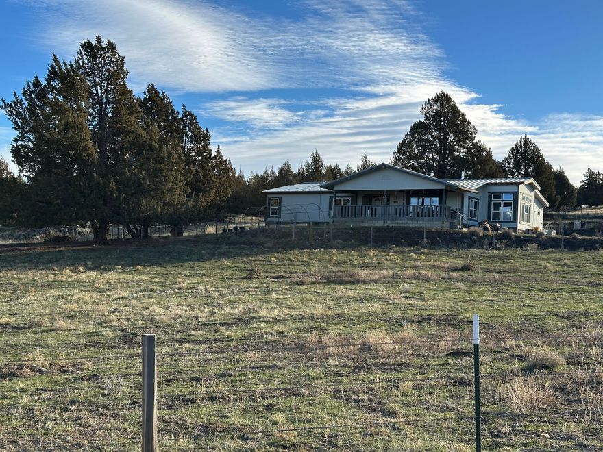 This expansive triple-wide home sits on a generous 20-acre lot and offers 2,550 square feet of living space, featuring three bedrooms and two and a half bathrooms. The property boasts a spacious open floor plan that includes a dining room, living room, family room, and utility room. The kitchen is equipped with a propane range, built-in oven, island, wet bar, and ample cabinet space. The primary suite is notably large and includes a bonus room or office, a walk-in closet, and a primary bathroom with both a shower and a soaking tub. The property is fully fenced and cross-fenced for animals, complete with a 2 stall animal shelter. Additionally, there is RV parking with hookups and a large shop measuring 36x72, featuring three roll-up doors. Home offers two propane funaces, 2 A/C forced air air conditioners and a Blaze King Woodstove.