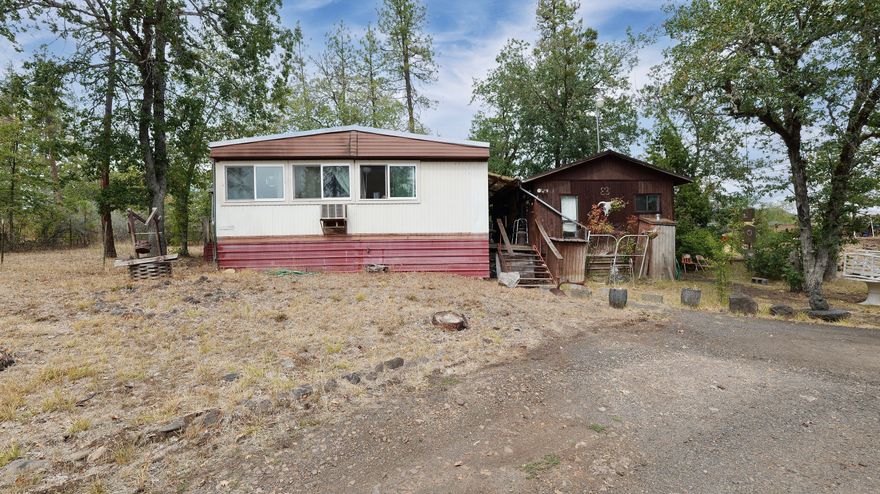 3-Bedroom, 2-bath, 1,152-sq. ft. 1974 doublewide on 1.35-acres with beautiful views and endless potential. Property also includes a 320-sq. ft. cabin near the main home, multiple sheds/outbuildings, and spacious decking/porches for outdoor enjoyment. Quiet, peaceful setting up off the highway with a convenient circle driveway. Home is livable but needs some TLC. The cabin, currently used for storage, has a bathroom and could be reimagined for additional living or guest space. Per seller, property has a good well and septic. Opportunities abound—fix up the home and cabin, or replace with a new manufactured home to create your dream retreat. Priced to sell, with a 2024 Jackson County RMV of $370,490, this property won't last at this price. Cash or owner carry options available!