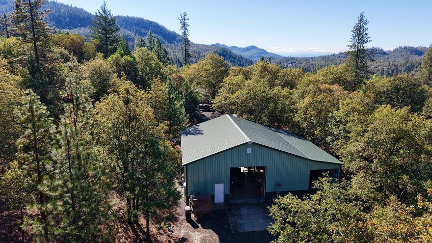 3.25% VA Assumable loan. Hard-to-find combo! 2013 Manufactured Home + Dream Shop + Views on 3.5-acres just outside Shady Cove. This 3-bedroom, 2-bath home features an open split floor plan with tons of natural light, Blaze King wood stove, and a private primary suite. Enjoy beautiful views and old-growth trees in a serene, private setting. Plenty of parking, including RV parking with full hookups. The incredible 40x40-shop is fully insulated, metal sided, heated and cooled, features dual pull-through 12.5' roll-up doors, a 10k lb lift, 200-Amp service with 220V, plus an additional 12x40-attached storage area (just needs a door to enclose). Both home and shop have newer heat pumps and the property includes a Starlink internet setup. Perfect for hobbyists, small business owners, or anyone seeking space for toys and projects. Peaceful, rural living with easy access to Shady Cove amenities — a must tour property with endless potential!