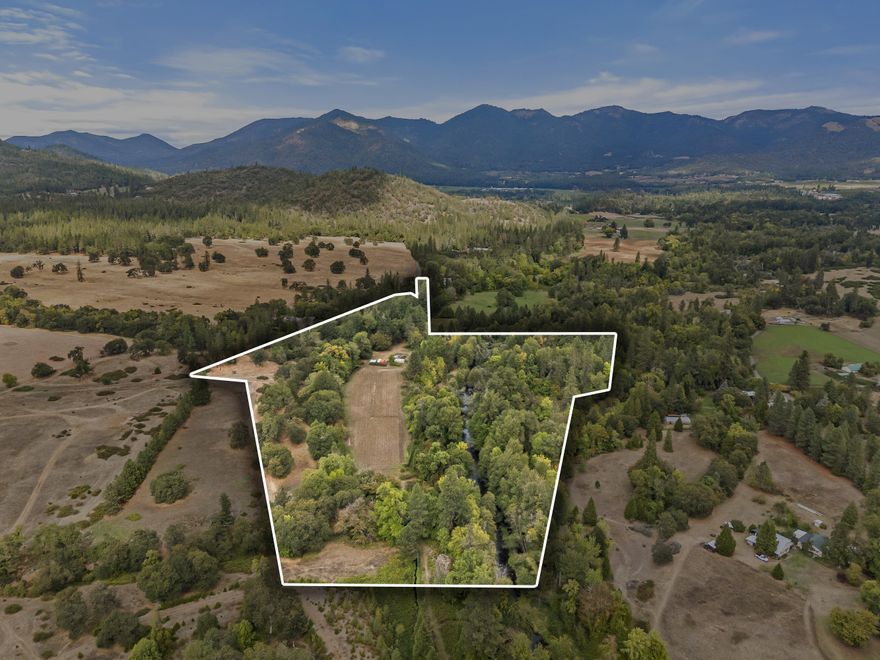 Rare Find in the Applegate Valley, Custom, Cedar home  w/ 1/3 mile of Williams Creek frontage traversing through this irrigated farm land. 33.3 ac. w/ 10 acres in water rights. 2 tax lots. Property is adjacent to Pacifica Gardens known for it's environmental education. Mostly level land with established organic gardens & orchard. Been used as a Certified Organic seed farm. Farming features 2 green houses, 3 separate fields, fenced & cross fenced. After a day in the sun enjoy the dipping pond for a cool down or wander along the tranquil creek trail. The 2 car garage/shop has been used for seed storage and processing, 2nd story has open living w/ separate office room. Home is open concept w/ solar tubes, French doors to patio off the living room. Kitchen offers a cook woodstove, custom Myrtlewood breakfast bar and large pantry. Separate utility canning room w/ farm sink. Bedrooms open to back deck. Wood floors throughout made out of Chinkapin and Myrtlewood. Lower level has root cellar.