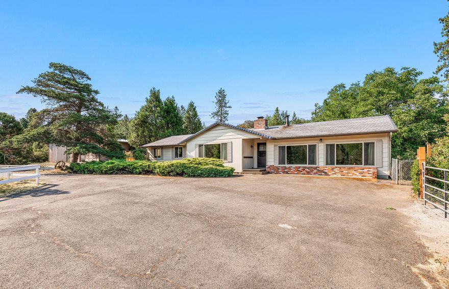 Do not miss out on this great home on 3.25 acres located on Old Stage Rd. in Central Point.  This 2256 sq. ft. home has 3 bedrooms and 2 bathrooms and features 2 separate living areas, a wood stove and also a wood burning fireplace.  The Primary bedroom is very large with a separate sitting area and has a nice sliding glass door that give you access to the covered back patio. Large picture windows throughout let you enjoy the wonderful views of your property and allow a lot of natural light to enter the home.  In addition to the home there is a 40 x 40 shop that has a large workshop with built in workbench, 1 single car garage and also a soundproof music room..  In addition to the shop the grounds are fully fenced with a pasture area with a couple of stalls and hay storage, a chicken coop, large raised garden beds, and also a potting shed/playhouse.  This property is located on a flag lot and sits off of the main road for peace and quiet that one would expect from country living