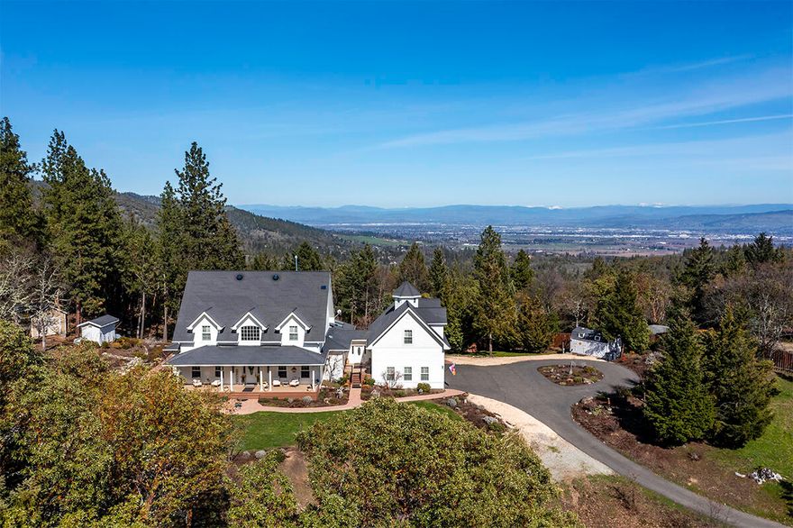 Stunning contemporary farmhouse w/breathtaking mountain views, nestled in the scenic hills of historic Jacksonville! Set on 10.02 acres, this gated 4,123 sq. ft. estate offers unparalleled privacy & seclusion while being just minutes from downtown shopping, Britt Festival, renowned wineries & more. Recognized as a National Firewise USA site, this stunning 4 bed, 3.5 bath home features two primary suites, including one conveniently located on the main level. Elegant foyer showcasing a grand staircase, soaring ceilings, rich hardwood floors & exquisite crown molding throughout. The gourmet kitchen seamlessly flows into the living & dining areas, boasting a butcher block island, Thermador range & a Butler's pantry w/wine refrigerator. Office with convenient built-ins, plus a finished bonus area above the 3-car attached garage. Park-like landscaping, charming covered front porch, rose gardens & flagstone patio w/fishpond & waterfall. Spacious deck w/exterior kitchen, BBQ.