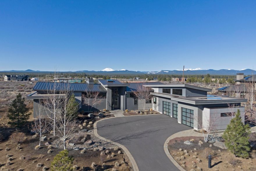 Nestled in the heart of Tetherow, this stunning single-level contemporary home boasts breathtaking Cascade views and seamless indoor-outdoor living. Designed for light and space, it features refined modern interiors and premium custom finishes.
The chef's kitchen shines with a quartz island, JennAir appliances, a wine fridge, wet bar, and water filtration system. Four bedrooms, including two master suites with spa-inspired baths, ensure exceptional comfort. Enjoy Sonos sound in the great room and patios.
Additional highlights include radiant heat, Daikin splits, Cat 5 wiring, and a spacious 3-car plus shop garage with a wash station. A metal spiral staircase leads to an 18x10 ft rooftop deck—perfect for sunset views. A true Tetherow masterpiece.