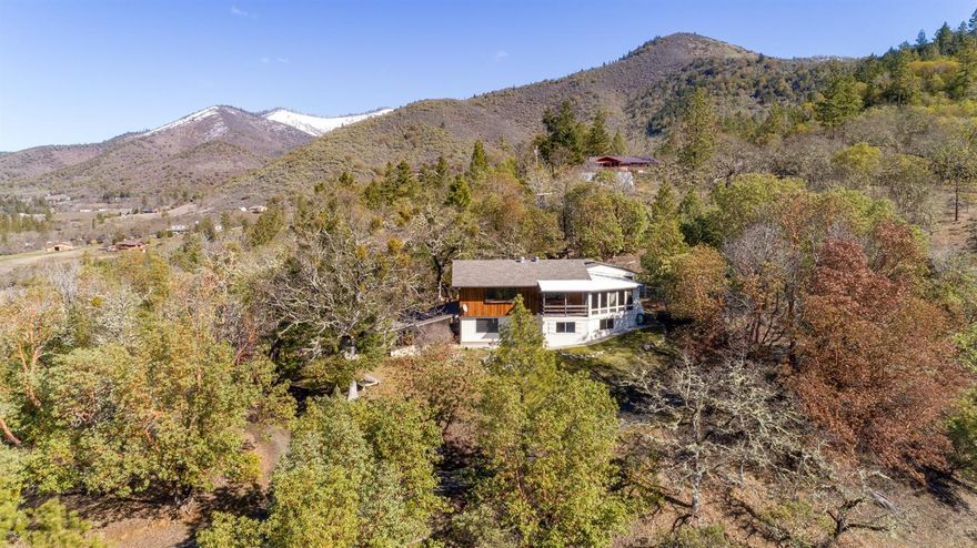 You will feel immediately at home in this comfortable home less than 20 minutes from Jacksonville. Private location on over 6-1/2 acres above the fog w/ amazing Applegate Valley views. The house features a large living rm w/ slate flooring & a wood stove open to a quaint country kitchen w/ lots of cupboard & storage space. A 16 by 24 sunroom utilized as a master bedroom is located off the kitchen with a sun deck that has stunning views of the valley below. There is another bedroom as well as a slate floor bathroom on the main floor. The lower floor w/ private access includes a 3rd bedroom & full bath plus a laundry area. Could be utilized for a 2 family set up. All appliances included in sale. The property includes a large carport, storage shed, workshop, raised garden beds, & an electric gate at the top of the property. Newer roof. Patio & deck areas on 2 sides take advantage of the privacy, serenity & abundant wildlife this property has to offer. Eligible for USDA financing.