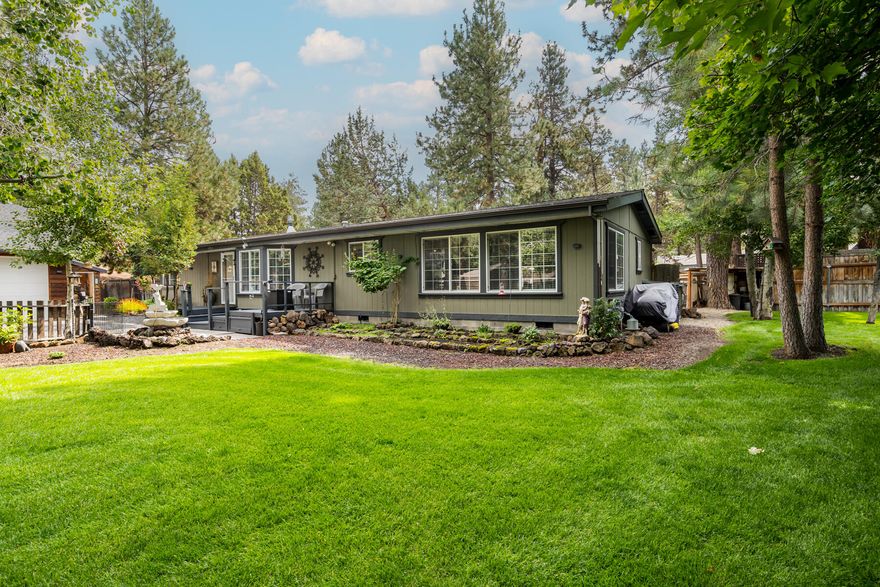 Private living with income potential on large, nearly half acre lot! This beautifully maintained manufactured home features a separate mother-in-law unit/guest house, amazing landscaped yard and hot tub, perfect for entertaining large groups or intimate BBQs. Built on a block foundation with detached 2-car garage, RV parking, tranquil water feature, and chicken coop for hobby or sustainable living. The expansive lot offers tranquility as well as privacy. Raised flower beds and fruit trees provide delicious fruits and fresh vegetables and fencing helps keep the deer from enjoying them. Don't miss this rare find combining outdoor lifestyle with practical amenities and rental income potential.