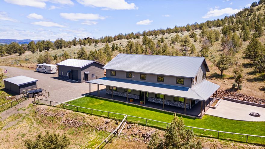 Where comfort meets country—this stunning custom home on 13.47 acres offers sweeping 180° views of the Crooked River Valley and O'Neil Ridge. Just 5 miles from Prineville and 13 from Redmond, this 3,240 sq ft home features 3 bedrooms, 2 bathrooms, and radiant floor heat. Step inside to a massive great room with 22-foot vaulted ceilings, wood beams, and a stunning stone fireplace. The chef's kitchen includes a 9x5 granite island, induction cooktop, double ovens, subway tile, and a walk-in pantry. Upstairs, a loft overlooks the great room and leads to a vaulted primary suite with soaking tub, tiled shower, and large walk-in closet. Enjoy the wraparound deck, covered kitchen, garden beds, playhouse with bunk beds, and a 30x36 shop with storage and a meat cooler cross-fenced with pastures, dog run, and space for an ADU or barn. Bring your animals, your toys, and your dreams —The Best of Central Oregon living.