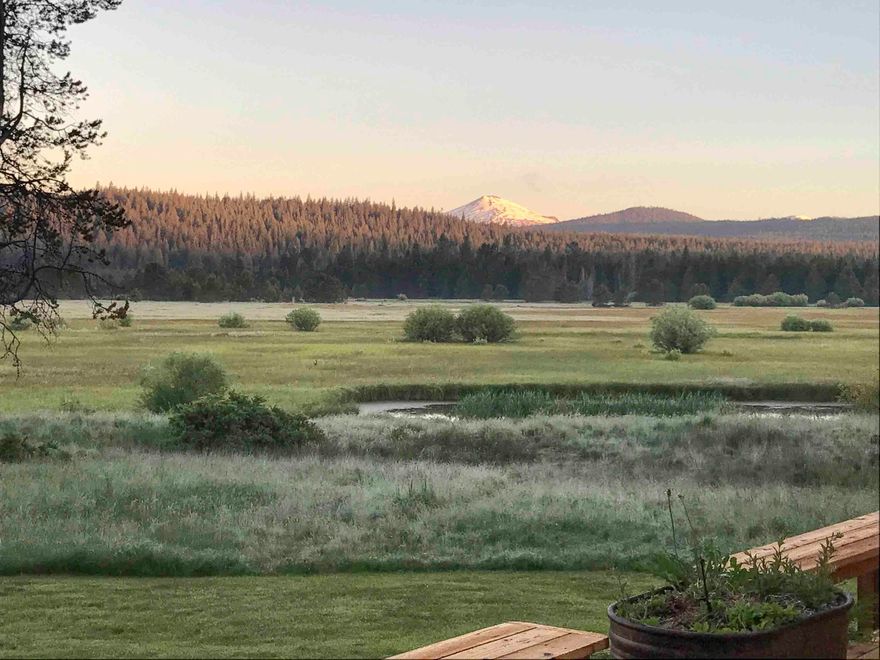 Nestled in the center of Sunriver is an exceptional NW style house offering unobstructed panoramic views of Mt Bachelor, the ''SunRiver'', & the Great Meadow. While possessing one the finest views in all Sunriver, this home is truly one of a kind.
Featuring 5 bedrooms (2 primary suites) & 3.5 baths, this home offers both ample space and comfort. Step inside to discover the warm knotty alder hardwood floors and the elegance of slate tile floors, w/ vaulted ceilings that create an open and airy atmosphere. Many custom items, such as cabinets & light fixtures were hand-crafted by Sunriver's original resident artist. A hallmark of this home are its grand windows, strategically located to capture the views from nearly every room. Wherever you are in this home, the outdoors is always present. The spacious deck is where you'll find room to host large gatherings, read a book or simply relax in the hot tub under the stars. This house, the location & its views is the essence of Sunriver.