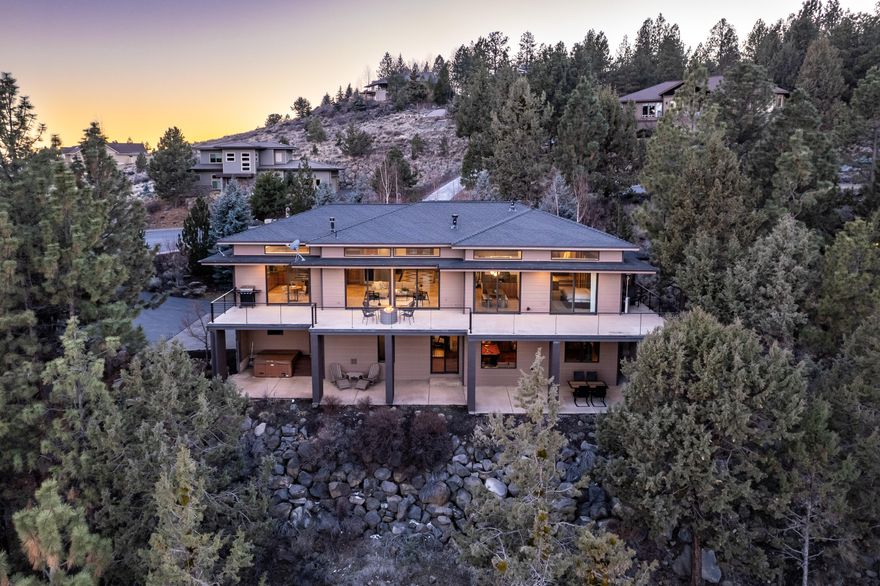 Stunning PANORAMIC mountain & City VIEWS from this Awbrey Butte contemporary home.  Open floor opens to a huge deck perfect for entertaining.  Chef's kitchen w/large island, hickory cabinets, granite counters, Viking refrigerator/freezer, 4 burner gas cooktop w/griddle, Bosch DW, Thermador microwave & oven, built-in wine cooler & walk-in pantry.  Spacious living area & dining room w/see-through gas FP.  Large primary suite w/access to deck, gas FP, Kohler infinity tub, dual sinks, walk-in tile shower, radiant floor heat & 2 closets.  Main level has a guest room, full bath and office w/built-ins.  Downstairs offers 2 bedrooms, bath, laundry room, theater room w/6 chairs, projector & screen, bonus room w/wet bar, kegerator, DW, big screen TV & pool table. Smart features include LED lighting and 24 built-in speakers controlled by Sonos app. 3.8 kilowatt solar power system (owned) & AC. Huge 3 car garage (988 SF) built-in cabinets.  Covered patio off bonus room w/hot tub.