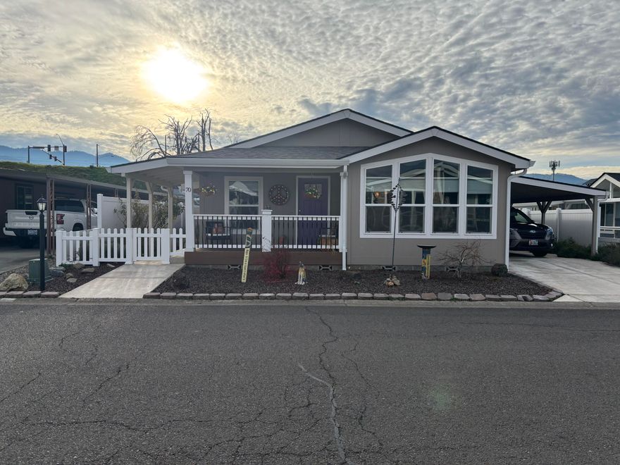 You will enjoy this sweet 2023 built 1620 sq ft Skyline home with 3 bedrooms and 2 full baths located in the sought after Mountain View Estates in Talent. The primary bedroom runs across the back of the home with a large walk-in closet and its own back door for convenience to the backyard and gazebo. The primary bathroom comes with a double vanity and generous size linen closet. Beautiful vinyl plank flooring runs through the home. At the front of the house enjoy the vaulted ceilings and open kitchen and living room space perfect for entertaining and relaxing. The kitchen is a delight with a beautiful custom solid wood slab island, Dekton countertops, pantry, farmhouse fireclay sink in addition to lots of cabinet space.  Big windows let in light at the dining nook and living space at the front of the house. The laundry room comes with a convenient utility sink in addition to access to a covered carport that is fenced and gated for a pet.  There is so much to love about this home!