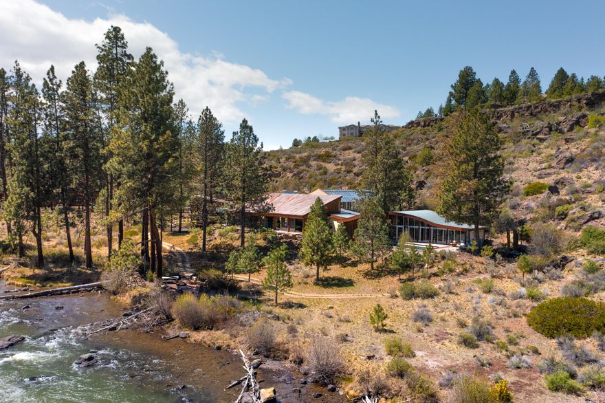 An inspiring Deschutes Riverfront setting in Bend on 6.6 acres w/over 900 ft of river frontage wrapped in nature & open space. Northwest modern single level design w/extensive use of rare reclaimed wood & recycled materials including ancient Redwood, walnut & aged metals. Artisan  finishes & custom art details w/Chihuly art glass entryway & Setziol wood carved panels. Grand scale living space w/perfect acoustics, large wood sliding doors that open to sounds of the river & abundant natural light fills the great room providing an inviting & uplifting atmosphere. There is also a large flex/exercise room that opens to back deck & pool. The huge garage merges seamlessly w/amazing greenhouse with multiple accesses into the gracious main hallway. There is also a separate guest house, a caretaker cottage & a 2nd garage/shop. This irreplaceable property provides the best vantage point to view kayakers, fish from your own backyard or cozy up around the fire pit. There is nothing else like it!