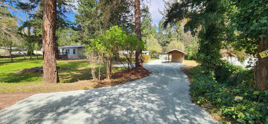 A Special Place To Call Home! Quiet neighborhood a short distance to the Rogue River and Chinook Park. This property is a gem! Almost an acre of level and useable space for outdoor living with majestic old growth trees. Featuring two decks, RV hookups, GPID irrigation, carport and storage sheds. New gravel driveway, parking and walkways with private driveway access. New $16K EcoPod septic system installed in 2023. This Palm Harbor Home is bright and open with vaulted ceilings, a smart split floor plan for bedrooms. Dining room space, galley style kitchen, mud room/laundry room open to the back deck. The light and airy primary bedroom has a walk-in closet.  All this is waiting for your finishing touches the way you want it. All information is deemed accurate but subject to change. Buyer to do their due diligence.