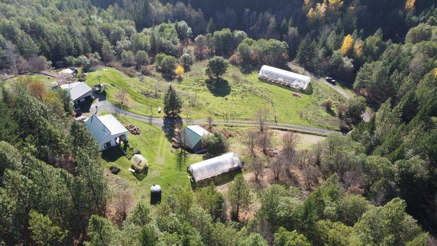 Call to schedule a showing today of this truly extraordinary, off-grid, solar powered home surrounded by Gov land with outstanding panoramic forest and distant mountain views, abundant wildlife, very private remote location with gated access only 6 miles from town. This one of a kind Terra-Dome Earth Sheltered Home was featured in the New Pioneer Magazine in 2016. This 2 bed/2 bath house was built directly into a hill leaving only the front of the structure visible to the outside world. The design is extremely energy efficient thanks to the earth surrounding the home + the addition of a Central boiler hydronic furnace, micro-hydro turbine, 3750-watt Solar electric system, and multiple water sources w/5500 gal storage. Ext. features include 3 greenhouses w/ new plastic, 800 sf studio w/ RV Carport + full hookups, 2 car det garage, 625 sf garden shed and a lovely custom stone patio from which you will enjoy the views and serenity. Home is environmentally friendly and low maintenance.