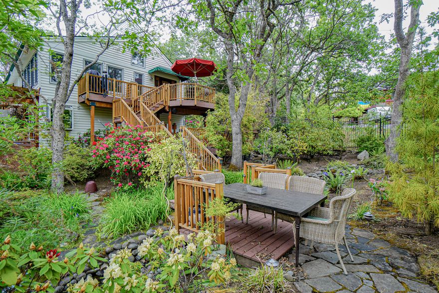 This open and light home sits on a huge .43 acre lot in a lovely Ashland neighborhood. The spectacular park-like grounds offer a bubbling creek and pond with mature landscaping. On the home's lower level, you will find all three bedrooms and a large family room with fireplace. The Primary Suite offers a gorgeous updated bathroom and sliders to the back patio. All bathrooms have been beautifully maintained and thoughtfully updated and renovated. Upstairs offers high, beamed ceilings, the open living room, half bath, spacious and bright kitchen, dining area and den. You'll love enjoying your beautiful yard from the many sitting areas and patios around the home. There is a detached garage perfect for storage.