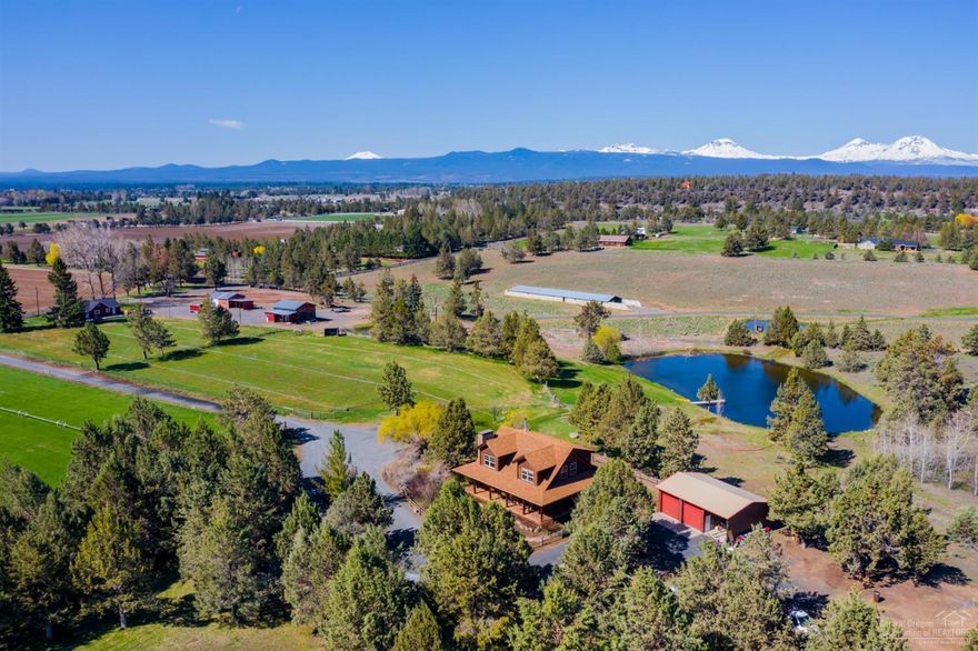 Gorgeous Custom Oregon Log Home nestled in the heart of Tumalo! Peaceful & private 20 acre property with 11 acres of irrigation rights. EFU zoning. Fenced & cross fenced, with 3 car garage, shop, 5 stall barn, hay shed, large pond w/dock & stocked with fish. This non-settling, low maintenance log home is beautifully crafted with the highest attention to detail. Main living area boasts a dramatic 24 ft vaulted ceiling, open concept living with lots of natural light streaming in. Cozy gas fireplace downstairs & wood burning stove in large loft. A combination of frame & log construction create beauty & warmth throughout. Gorgeous hickory cabinets & Juniper flooring complete this stunning Central Oregon custom home. Kitchen includes a center island, plenty of storage & SS appliances. French doors leading out to backyard with big views of property & water feature leading to the pond. Take in the views from the covered wrap around porch. Property also includes the charming original farmhouse