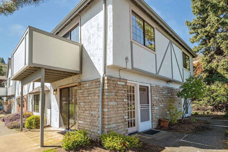 This affordable 2-story end unit condo resides in the peaceful Tudor Heights Condominiums at the top of the complex, conveniently located to all that Ashland has to offer. The open floorplan includes a built-in bay window seat off the kitchen perfect for informal dining, entertaining or reading. Large windows let in an abundance of natural light with mountain views to the east from both floors. There is plenty of counter space in the kitchen for the cook and a conveniently located half bath on the main floor.  Off the living room enjoy a patio for relaxing or taking in the surrounding mountain views. The inside has been freshly painted along with new carpet, and new toilets. Two bedrooms and a full bath are upstairs with one bedroom having balcony views. Unit includes a covered parking space and storage shed. Conveniently located near the shared laundry facility, mailboxes and carport. Lush greenery, privacy, and a peaceful atmosphere make this retreat the ideal place to call home.