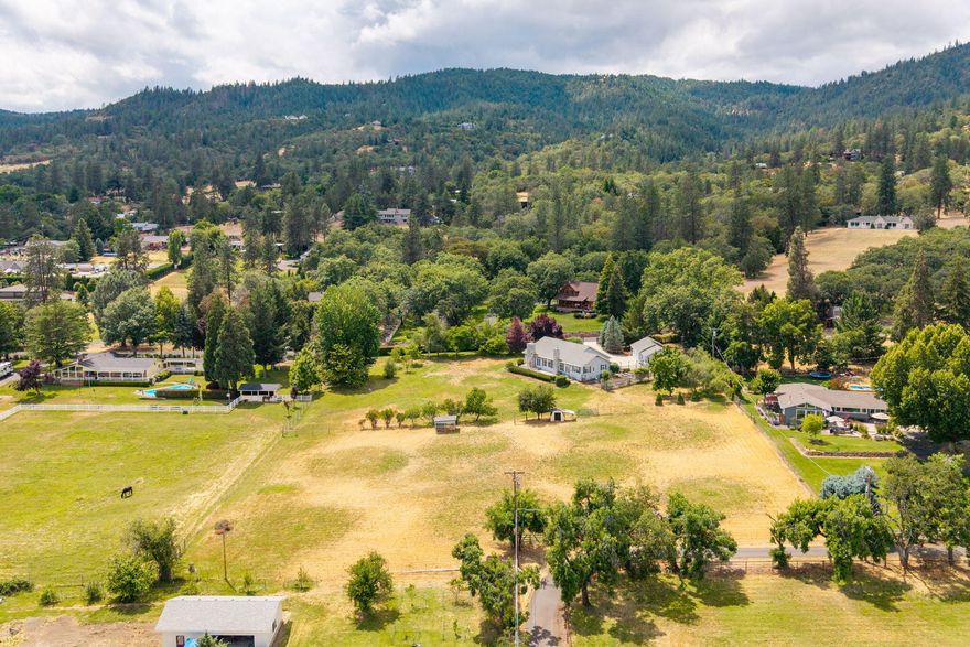This is the reason why people want to live in Southern Oregon; this single-story West Hills ranch style home is located on a quiet cul-de-sac minutes from historic Jacksonville on 2.75 acres, providing a country feel w/ the conveniences of town. Lots of room for hobbies w/ a detached 2+ car garage w/ a separate workshop, rm for RV parking, & guest qtrs w/ a full bath & kitchenette area. The ranch style home features a wide central hallway w/ rms down each side, w/ amazing panoramic views. The right wing has a living rm, formal dining w/ a built-in buffet, large family rm w/ a woodstove open to the kitchen which features a Viking range, wall oven & windows on every side that frame the spectacular views. There is a large pantry/laundry rm adj to the kitchen, leading to a fenced garden w/ raised garden beds. The left wing has 2 primary suites w/ ensuite bathrms as well as an additional bedrm & bath. The grounds are fenced & set up for animals, & a patio outside perfect for entertaining.