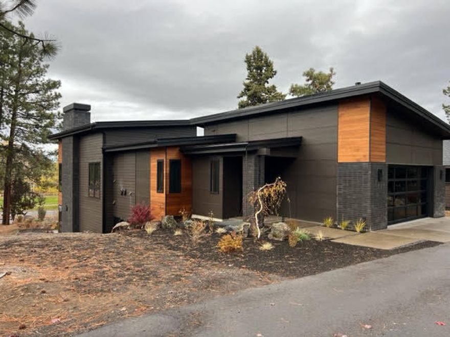 Nestled along Farewell Bend Park and the Deschutes River, this modern two-story house with industrial finishes is a stunning blend of contemporary design and natural beauty, its sleek lines, steel accents, and large windows offer a lovely glimpse of the breathtaking park and river view beyond. The house is an architectural masterpiece with clean lines, and a combination of materials that create a modern industrial aesthetic. The facade is covered in a combination of dark gray and black, coupled with rustic cedar. Large expanses of glass offer a seamless connection between the interior and the picturesque river park. The interior design embraces the upscale theme with a neutral color palette, accented by warm wood and metal finishes. The living room features a floor to ceiling fireplace,  oriented towards the large windows, framing the deck and views. This modern two-story home with industrial finishes seamlessly blends contemporary design with the beauty of its natural surroundings.