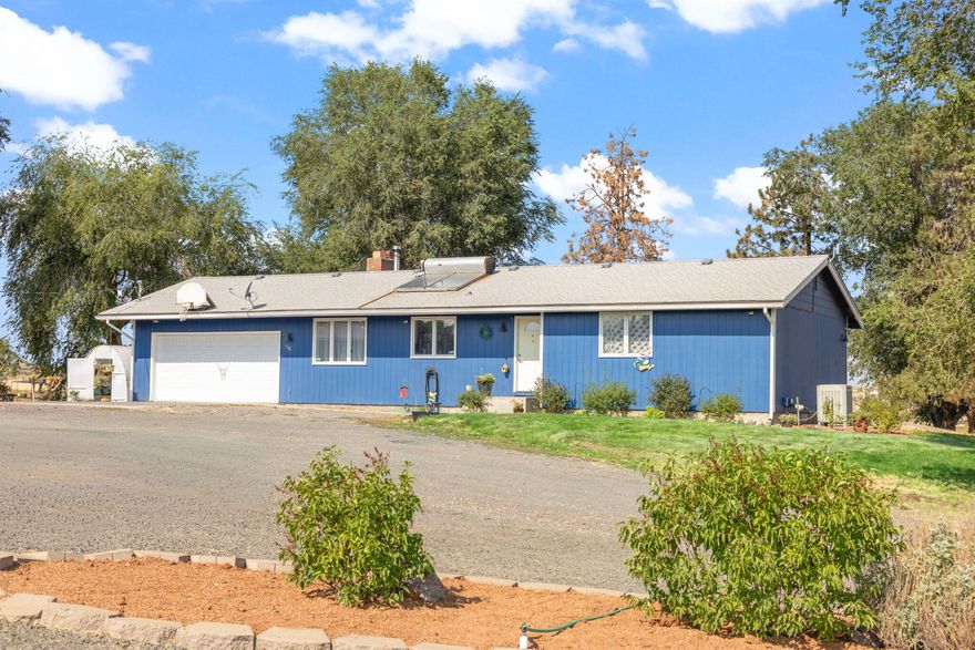 Experience peaceful country living on 1.92 irrigated acres, surrounded by farmland and serenity, while enjoying a spacious 2,388 sq ft home designed for multigenerational living. Upstairs offers 3 bedrooms, 2 full baths, a dual wood-burning fireplace, and open living areas filled with natural light. The lower level provides incredible flexibility with a family room, kitchenette, laundry, large bedroom, and bonus room—perfect for guests, extended family, or private living quarters. Outdoors, you'll find two large shop/storage buildings, covered RV parking with attached storage, additional sheds, a small carport, and an attached double garage. Plenty of room for hobbies, equipment, and projects. Lovingly maintained and move-in ready, this property combines functionality, space, and tranquility—an ideal retreat to call home.