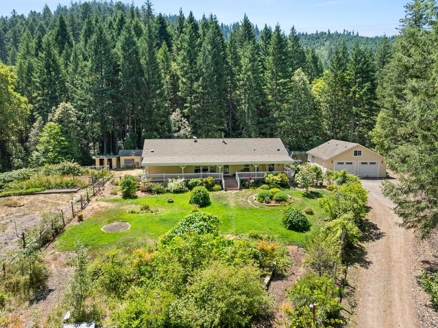 Full privacy! Assumable loan! Inspiring views from the full-length covered deck make this gardener's paradise a true slice of heaven. The home is a cut above with a beautiful modern floorplan and distinctive architectural features including impressive 9' tall ceilings, large primary suite, front and back decks and two living rooms. Wonderful large two-way garage with full bathroom and bonus rooms could be used for many purposes with a little imagination or converted to an ADU. Zoned irrigation. Bring your toys, this property backs to 600 acres of public land and is very close to Lake Selmac. Starlink internet may be transferable. List of yard equipment available for purchase. Assumable loan at 3% makes this a very smart and exciting purchase, ask for details! The 10 acre lot has potential for dividing as well. What a great property!