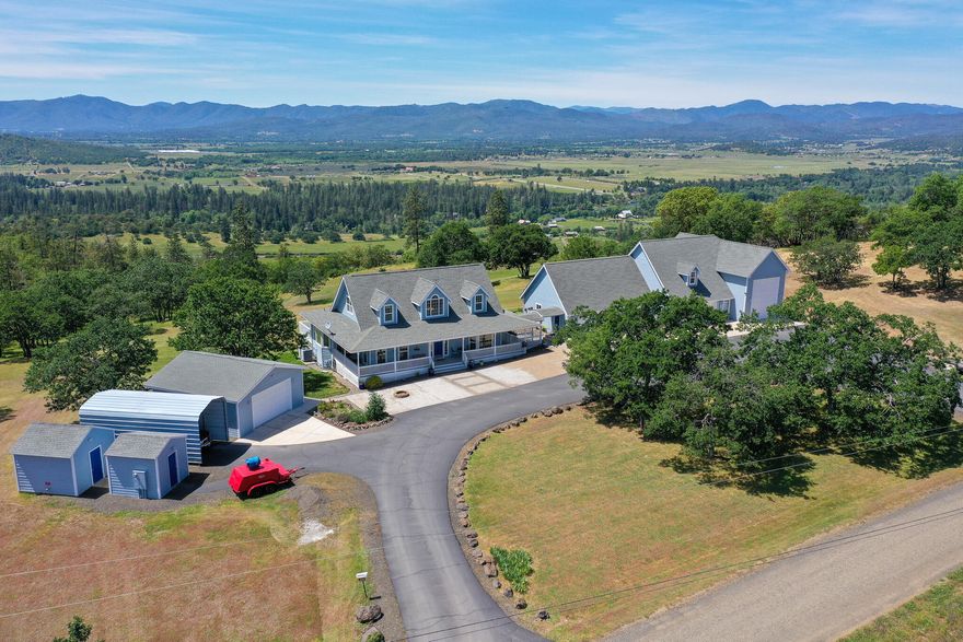 Perched on a mountaintop saddle with unparalleled views of Mt. McLoughlin to the East and Sam's Valley to the West is a car lover's dream.  This 2,562 sq ft home sits on 6.06 acres with covered secured storage for 7 vehicles and a shop space big enough for a vehicle lift or small RV.  An additional 410 sq ft Flex space over garage.  Shop spaces also include integral wood shop, metal shop and full bathroom with laundry.  Within the home you find the primary bedroom (with coffered ceiling) and bath on the main level, along with living room, dining room, half bath, and kitchen with breakfast nook, sunroom/office, and laundry room.  Living room has vaulted ceilings and gas fireplace.  Kitchen has granite countertops, island and pull out shelves.  Upstairs are 2 bedrooms and a full bath.  The water from the wells is supplied to the entire facility through a water softener and the house has built-in fire suppression.  There are too many amenities to list, ask your agent for complete list.