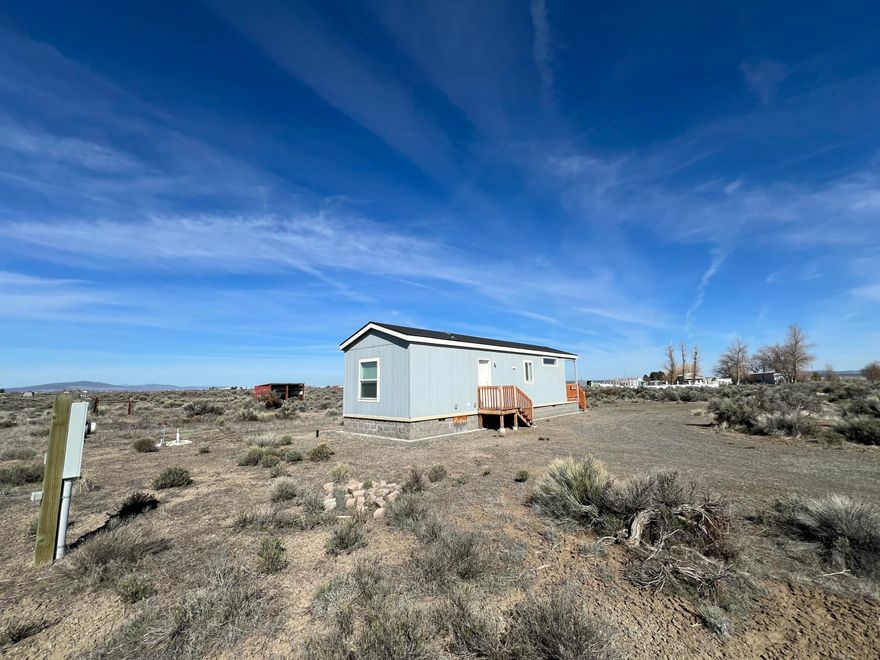 Like new! Welcome to peace and tranquility in this beautiful, nearly new home built in 2021. Located just minutes from all the amenities of Christmas Valley, this well-maintained property offers modern comfort and high desert charm. Inside, you'll find durable laminate flooring throughout, crown molding and a spacious kitchen with ample cabinet space—perfect for everyday living or entertaining. Relax on the cozy front porch as you take in breathtaking sunsets, or enjoy sweeping desert mesa views from the bedroom window. Distant mountain vistas add to the serene, open feel of this picturesque setting. The property offers a fully fenced area ready for livestock, making it ideal for hobby farmers or those seeking a rural lifestyle. The home is also built on stem wall foundation and has never been moved from the original site, qualifying the home for a range of financing options. All this, while still being conveniently close to town, shopping, dining, and the gas station.