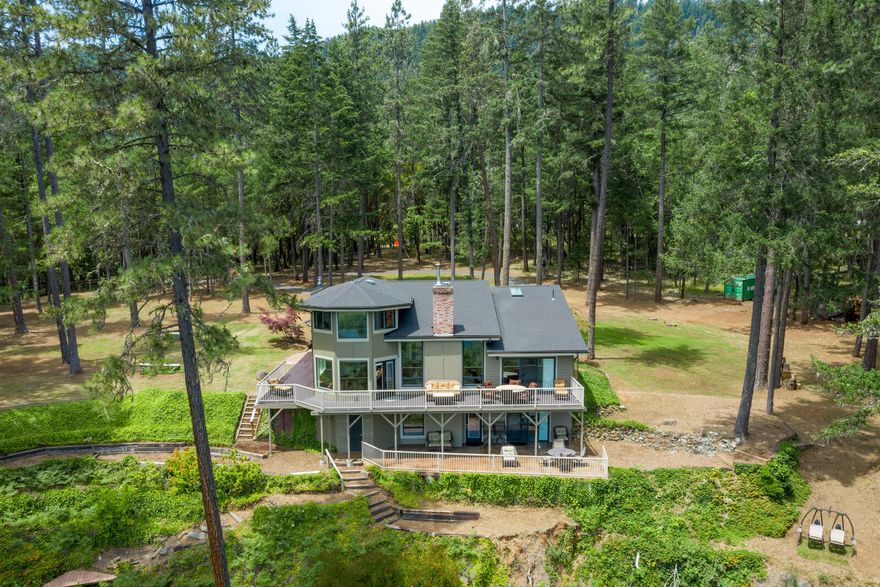 All of this exquisite home has been redesigned and updated.  There are sounds of the river from every room creating a tranquil and peaceful setting to enjoy. The architectural design of this home, 4,363 sq ft on 3.79 acres, creates feelings of airy openness at the edge of the world. Main level offers open concept kitchen featuring built-in appliances, quartz counters, a large island and ample storage. Living space boasts 2 fireplaces and bonus room for entertaining. Private master suite features custom tile shower, soaking tub and expansive walk-in master closet. Top level shows 3 large bedrooms, 1 full bath with massive windows and sweeping river and landscaping views. Lower level provides a separate bed and bath, living room, wet bar, and fireplace. This property offers ample room for a shop or guest house.  Situated on the Wild and Scenic Section of the Rogue with an island to go fishing, swimming or simply relax