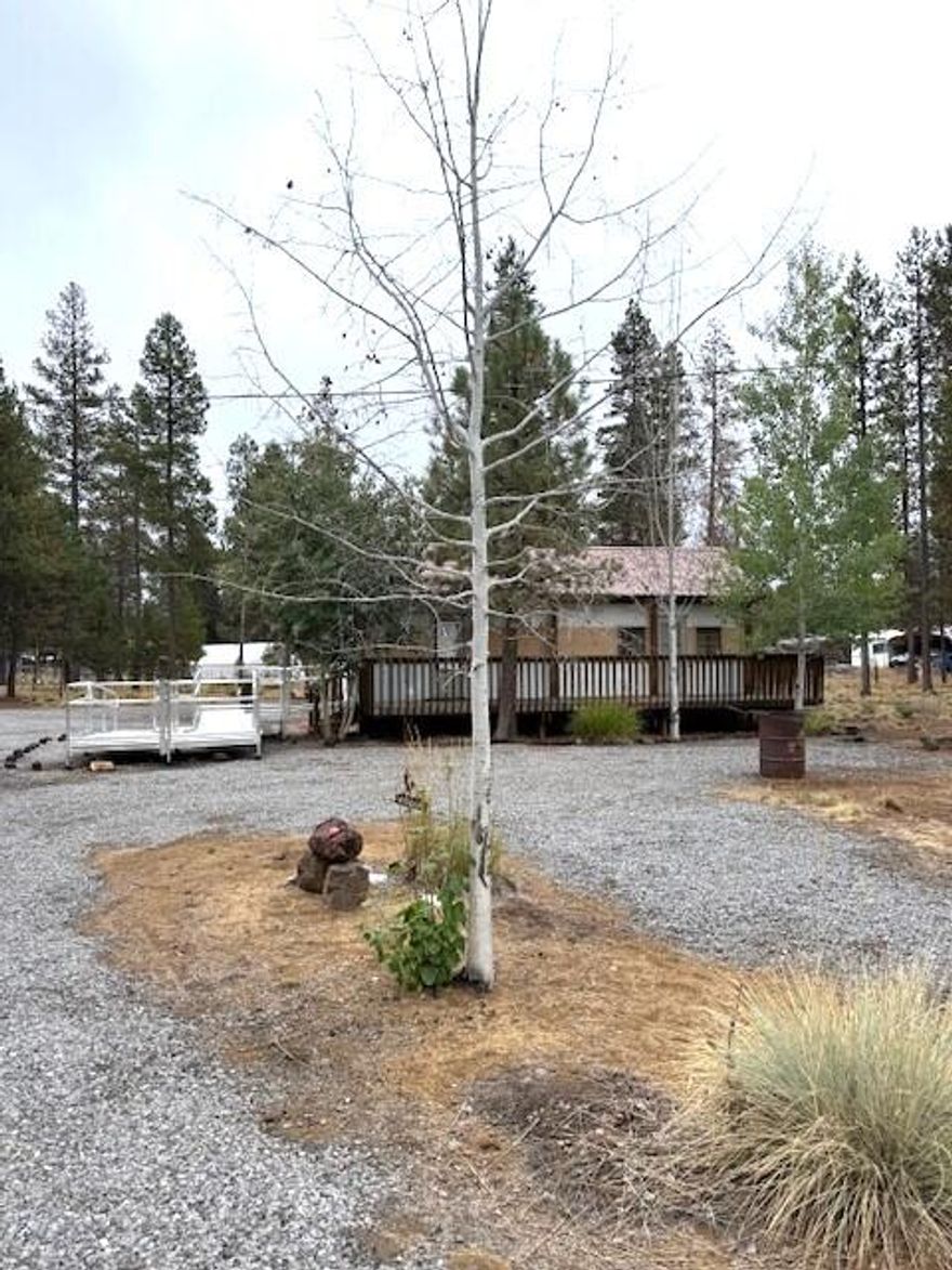 Discover this beautiful and well-maintained lot featuring a 1963 Single Wide, 1 bed, 1 bath manufactured home and four spacious sheds—two with room for covered parking! This property offers endless possibilities on approximately 1.13 acres with a fenced and gated entrance. Enjoy an accessible ramp leading up to the wood deck, a gravel driveway, and the option to remove the existing mobile home to build your dream residence. The property is connected to city sewer and water. Conveniently located near recreational areas, with easy access to Hwy 97 for commuters. Paulina, East Lake, and Newberry Crater are just minutes away. Don't miss your chance—schedule a tour today!