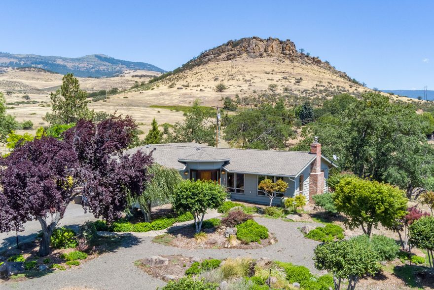 Incredible panoramic views of the Siskiyous & Pompadour Bluff from this beautifully updated, single level home. Sitting on 25 acres with irrigation rights, this home provides privacy and a large barn/stable for animals- truly a wonderful getaway yet just 10 minutes to downtown. This well cared for home has an open floor plan with vaulted grass cloth ceilings, solid teak doors and natural light. The great room has concrete finished flooring, a wood burning stove that provides warmth and ambiance and opens to a large deck that has views of Pompadour. The kitchen has custom cabinetry and high end appliances along with a large granite topped island. The bedrooms sit away from the living space with a large primary suite with & office space that opens to the deck. The en suite bath is spa-like and provides a wonderful oasis. This property also has a detached guest house that sits away from the main house & has potential for many uses.  Don't miss your opportunity to live the Ashland dream.