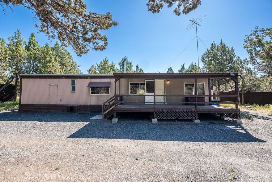 Welcome to 8012 Hood Circle—an affordable, flexible opportunity in beautiful Juniper Canyon. Just 15 mins from Prineville, this flat, tree-lined 1.91-acre lot offers privacy, peace, and space that's hard to find at this price. The 728 SF 1976 manufactured home has 2 beds, 1 bath, and easy main-level living. It's simple but functional—ideal as a starter home, weekend retreat, or place to live while you build. Enjoy a large covered porch, gated driveway, full fencing, and a 3-bay outbuilding for storage. Bonus fenced area for a dog run, garden, or chickens. Power, septic, and water are in place—move in or start building right away. Convenient access just off Juniper Canyon Rd. Owner carry financing considered with strong terms and qualified buyer. Don't miss this usable, buildable slice of Central Oregon with room to grow.