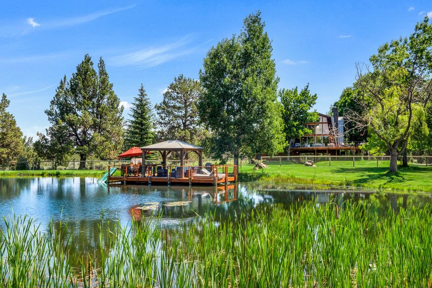 This magic home resides down a ¼ mile maple tree lined driveway, nestled in a rare 19.7 acres in Tumalo with majestic views of the Cascades, irrigated pasture (11+ acres water rights) and swimming/fishing pond. Quick access to Bend, public lands/trails and a few short minutes to the prestigious Cascades Academy. This magnificent home has a new metal roof, hardwood floors, updated windows and designer touches throughout. Expansive views from all sides of the open floor plan with two decks looking towards the Cascades and the sandy beach swimming pond.  Main level has vaulted ceilings anchored by a wood burning fireplace & large windows framing beautiful sunsets over the mountains.  Primary suite is upstairs with an attached bathroom & large loft area.  Two generous sized bedrooms on the main level + full bath.  The first floor has a second wood burning fireplace, full bath, laundry + two additional bedroom/office space. Fully fenced property and newer insulated 1,500 square foot shop.