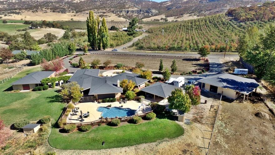 Marvelous craftsmanship and exquisite attention to detail! This stunning home is a Frank Lloyd Wright Prairie Style Reproduction and features gorgeous views overlooking Medford and the Rogue Valley. Conveniently located just minutes from Medford. Elegant floor plan captures views from office, kitchen, dining, great room and master suite. Home has exquisite woodwork including gorgeous Brazilian Cherry Wood floors, beautiful walnut cabinets and natural wood molding throughout. The island kitchen is a dream with handmade custom cabinetry and high end appliances. Elegant master has beautiful private en-suite bath and large walk-in closet with custom built-ins. Property features over 5 acres with irrigated pasture, separate shop/garage, guest (pool) house, second shop/barn with 3 stalls and turnouts, Approx 1/4 acre of blueberries, raised garden beds and plenty of room for parking all of your toys plus an in-ground pool. Call for complete Amenities List and Virtual Tour Link!