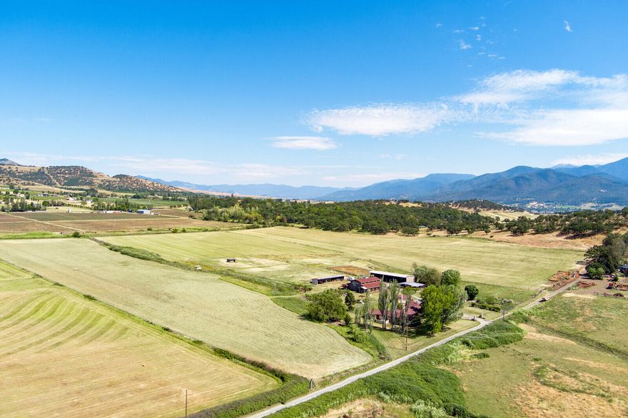 You know how every once in a while you come across a place that just feels magical? This is one of those places. Close to everything but located at the end of a private road, the property entrance is framed by large stucco pillars. The sprawling single-story Spanish style house was built by Hollywood movie actors. Surrounded by 360-degree valley views, this is an operational farm, w/ 2-3 annual hay cuttings. There is bountiful water w/ irrigation rights thru TID on a pressurized line that serves this property only & also fills a small pond. A year-round watercourse can be used for irrigating the yard & paddocks. There are numerous other buildings, including a bunkhouse, a movie worthy 100-year-old barn, shop, & hay & storage bldgs. The entire property is fenced/cross fenced & includes figs, peaches, apples, persimmons, as well as grapes & thornless blackberries. With a premium location, plentiful water, & wonderful grounds, this farm is a rare opportunity you won't want to miss!