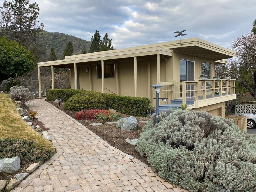 Meticulously maintained Mid-Century Modern with Expansive Mountain and Valley Views! This gorgeous 2,552 sf 3 bedroom, 2.5 bath, two-level home features unique architectural styling, amazing natural light, hardwood and travertine flooring and quality updating including a granite and maple kitchen with stainless appliances, stylish baths, two dual-fuel fireplaces, three skylights and almost 500 sf of wrap-around view decking. The home is wonderfully sited on a ¼ acre panoramic lot landscaped by a master gardener incorporating tiered beds, 10 fruit trees, gorgeous plantings, drip and spray irrigation and excellent deer fencing. Downstairs is a self-contained guest suite with private entry, bedroom, bath and living space, plus a laundry area that could easily accommodate a kitchenette with outside access. There's excellent parking, room for a smaller RV, great storage, an oversized single garage, newer HVAC and low-pitch rooflines ideal for a future solar panel upgrade.  A Joy to Own