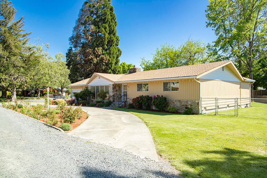 Welcome to a peaceful, spacious, and beautifully maintained single-level home. With 2,200 square feet of living space on over half an acre, this retreat blends comfort, privacy, and potential. Curb appeal greets you with a wide circular driveway, blooming flower beds, and a warm, welcoming feel. Out back, the fully fenced yard opens to Clara Avenue through a gated entrance—ideal for extra parking, boat or RV storage, or future plans like an additional dwelling (ADU). A garden shed and 500-gallon water tank help keep your landscape thriving. Grab a nectarine or apple from the trees, and enjoy lounging in the shade of the covered patio - also great for entertaining! Inside, enjoy two living areas, a kitchen with pantry, three bedrooms, two full baths, and a sunroom/office that connects to the scenic backyard. You'll love the abundant storage, full laundry room, and garage with dedicated shop space. All just minutes from shops, restaurants, medical offices, and more.