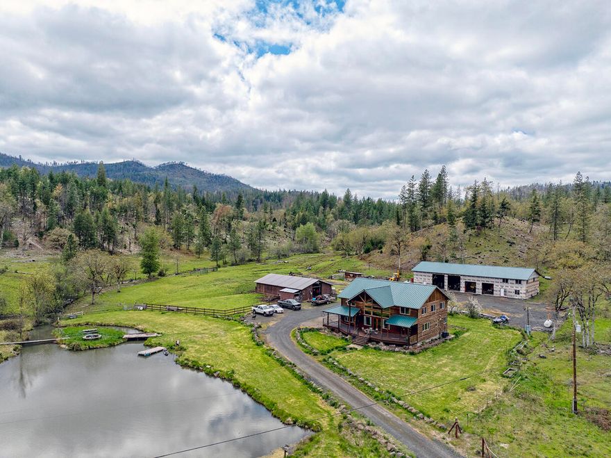 Tucked away in a peaceful, wooded setting, this private retreat offers beautiful views of your own small lake, complete with an island, firepit, and BBQ area for ultimate outdoor enjoyment. Surrounded by towering Douglas firs and open meadows, the property includes a 36x60 barn, a 3-bay shop with living quarters, and access to nearby riding trails—perfect for horses, 4-H, or extra storage. Inside, you'll find charming details like tongue-and-groove ceilings, a sunken tub, a spacious bonus room, and French doors in the primary suite that open to serene lake views. A large walk-in pantry adds convenience to this unique country haven.