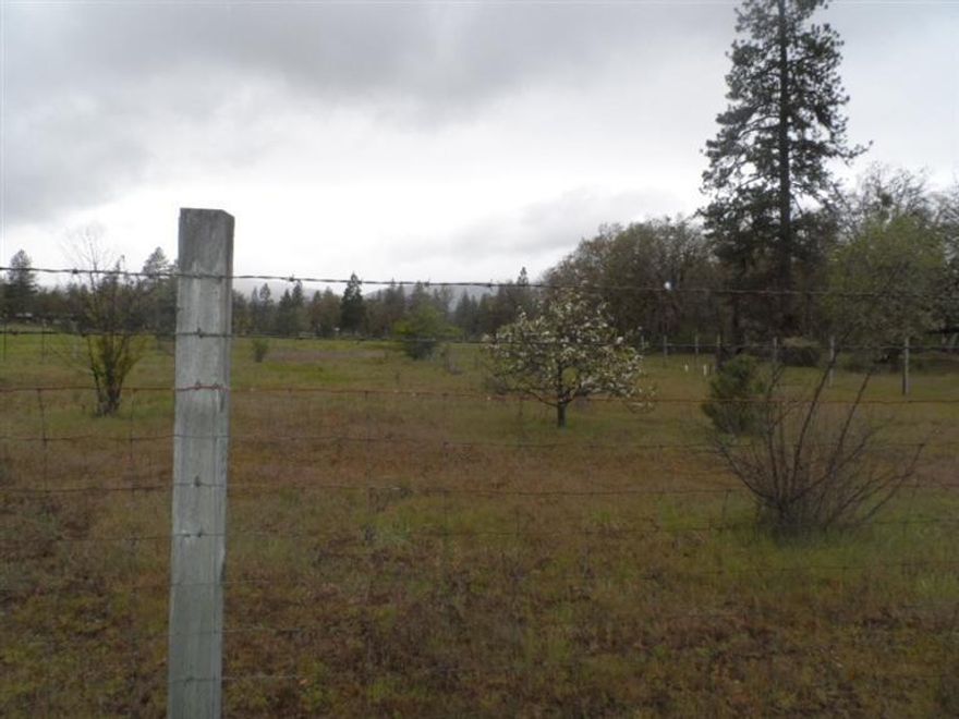 This is a great parcel on the east fork of the Illinois River secluded yet close to town. This level partially wooded acreage offers a perfect home site surrounded by whispering pine and majestic oak. There is also abundant pasture and garden areas as well as a fenced orchard. The well is in with a 110 volt pump, storage tank and water distribution system. Well drilled in 2000, tested 20 GMP. The existing covered camp trailer and deck are included.