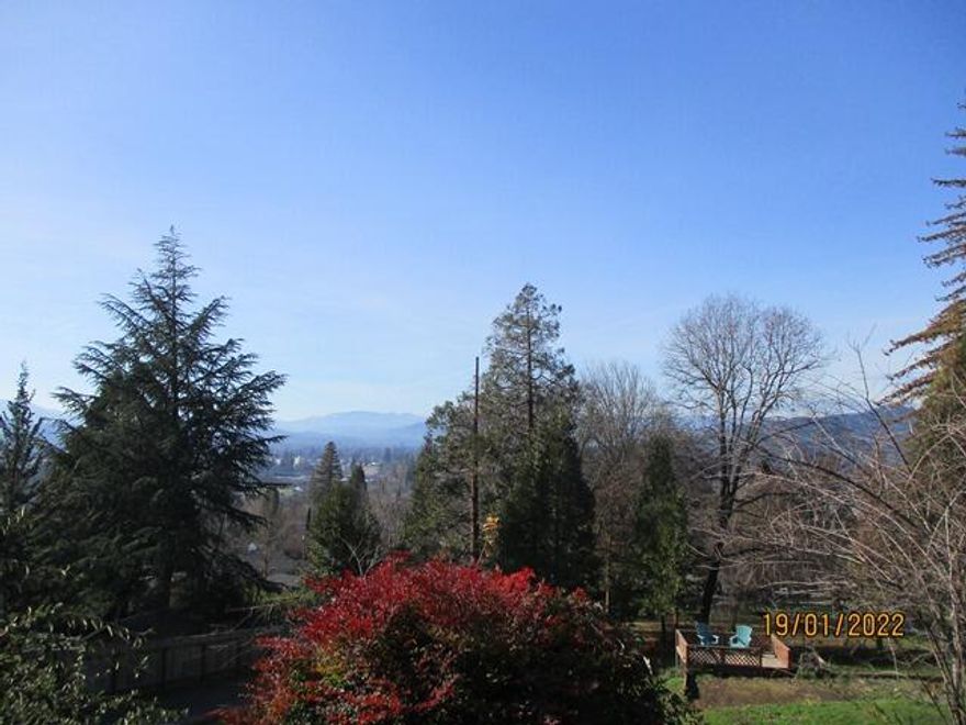 Beautiful panoramic mountain views from this home located in town. Built in 1971 with wrap around deck is this 4 bedroom, 2-1/2 bath house on .75 of an acre. Inside includes 2436 sf, living room with built in entertainment center, wood burning fireplace, ceiling fan and picture windows to bring the outside in. The spacious kitchen includes granite tile counters, eating bar, window over the kitchen sink, pantry closet and plenty of cabinetry.  The bright dining room has access to the front deck handy for eating inside or out. Family room has a huge Blaze King wood stove and ½ bath. Master bedroom with built-ins, walk in closet, master bath with jetted tub and walk in shower.  Interior laundry room, french doors and ceiling fans throughout.  RV hook ups, fenced garden area, shed, fruit trees and irrigation. New furnace in 2018. Recently painted inside and out and plenty of storage areas. Country feel but with city services.  Move in ready!